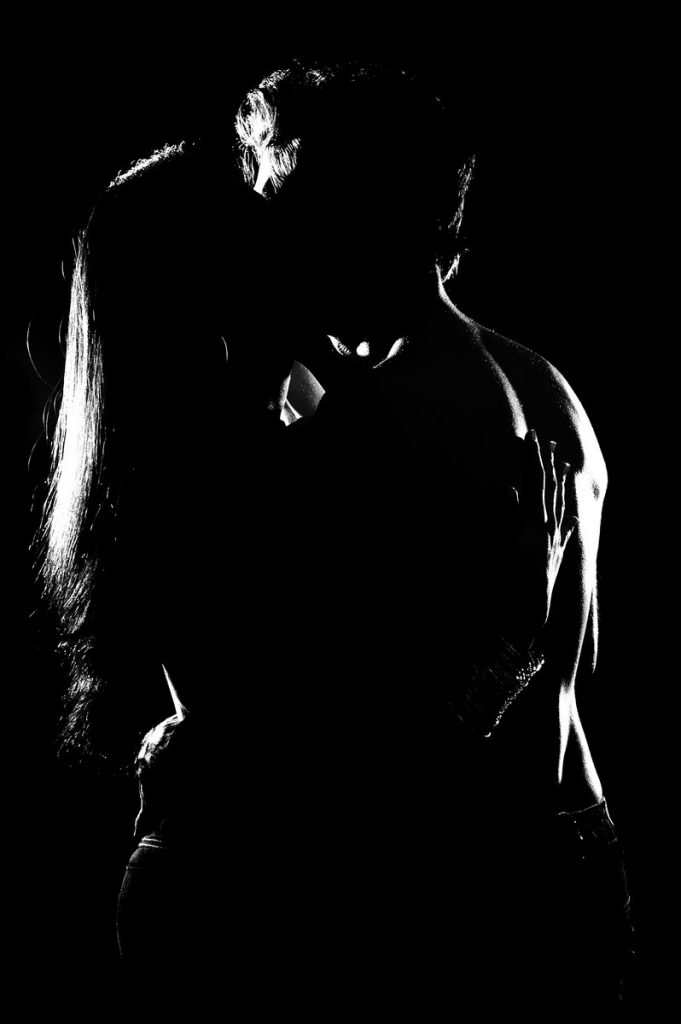 a naked couple kissing in the dark