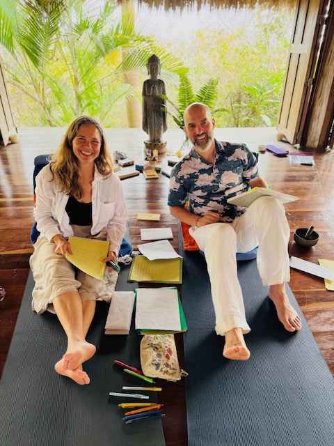 Jim Kemp, PsyD and his wife, Lisa holding notepads while lounging on the floor
