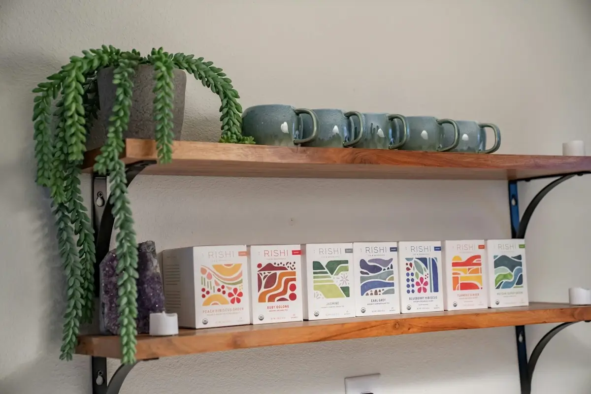 Tea boxes, mugs, and a plant sitting on shelves